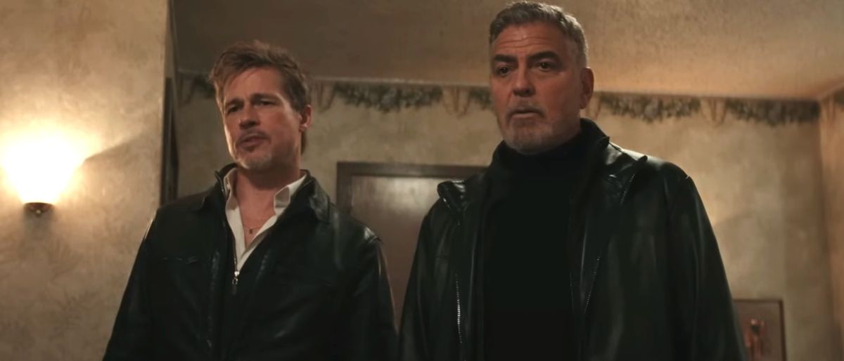 Brad Pitt and George Clooney stand together looking concerned in Wolfs.