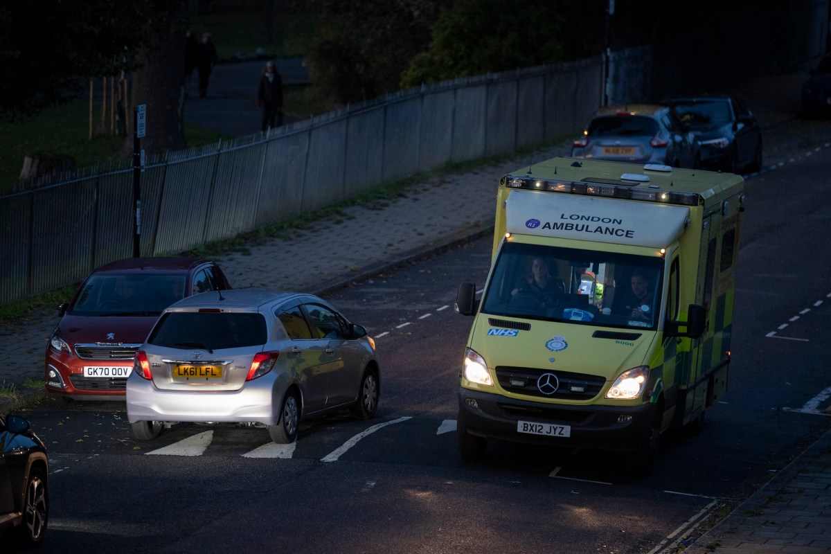 Seen from a high perspective, a London Ambulance passes an oncoming car at dusk on a residential street in Lambeth, south London, on 27th October 2023