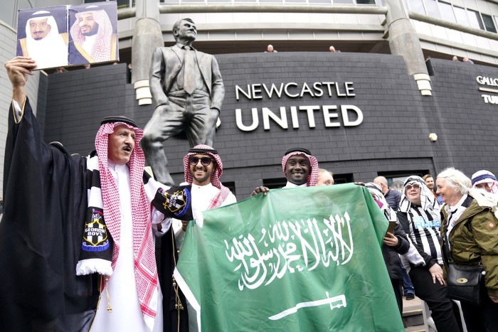 Newcastle United fans outside the stadium hold up a Saudi Arabia flag ahead