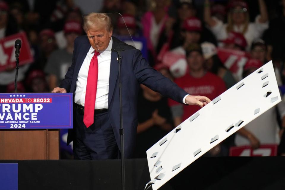 Former president Donald Trump removed signage that fell on top of his teleprompter at a rally in Reno, Nevada (AP)