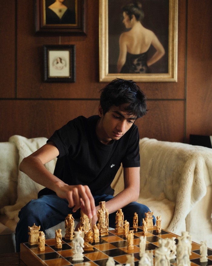 Sohum plays chess at an antique board. The works on the wall behind were acquired from a private collector in New York