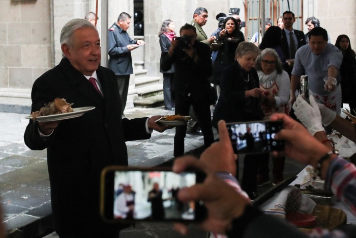 A man holding a plate of food faces a scrum of journalists