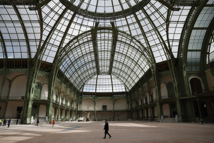 Interior of a large French beaux arts building, with high arches made from green-painted metal, lined with glass, like the old Crystal Palace or Kew Gardens,  and bathed in natural light