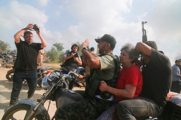 Palestinians transport a captured Israeli civilian from Kfar Azza kibbutz into the Gaza Strip on Oct 7 2023