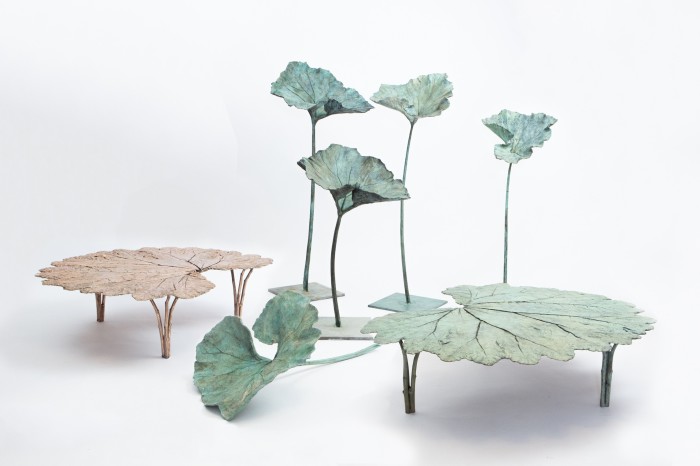 Two large tables, made of bronze, where the top is the bronze cast of a giant leaf, one copper coloured, one in a verdigris shade. There are also verdigris-coloured bronze casts of smaller leaves, mounted on stands and plinths