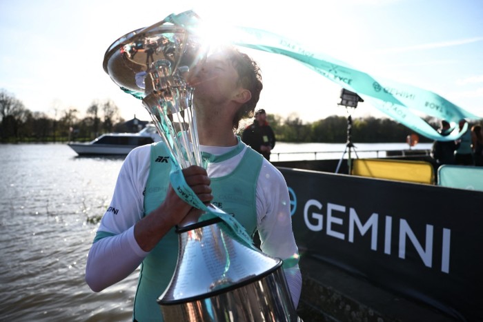 Cambridge university’s Augustus John poses with the trophy after winning the 2024 boat race against Oxford