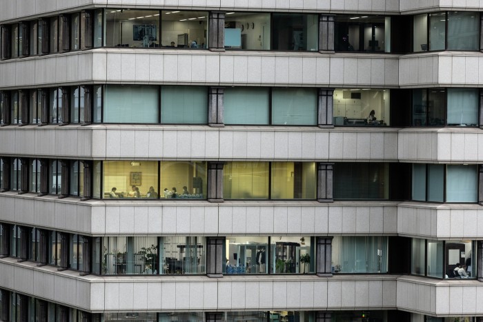 Office workers in a grey Tokyo commercial building, as seen from the outside