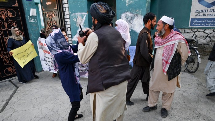 A woman protester scuffles with a member of the Taliban outside a school in Kabul