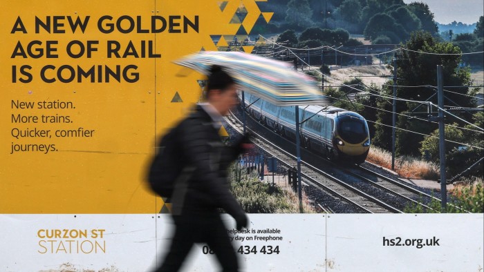 A person walks past the perimeter of the HS2 high speed railway construction site