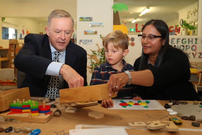 Anthony Albanese reaches into a box held by an adult supervisor at a childcare centre in Perth