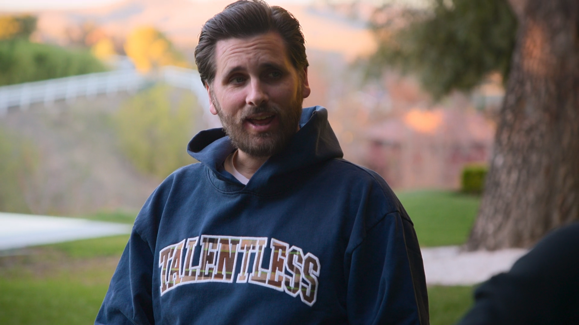 Scott Disick wears a dark blue, almost teal hoodie.