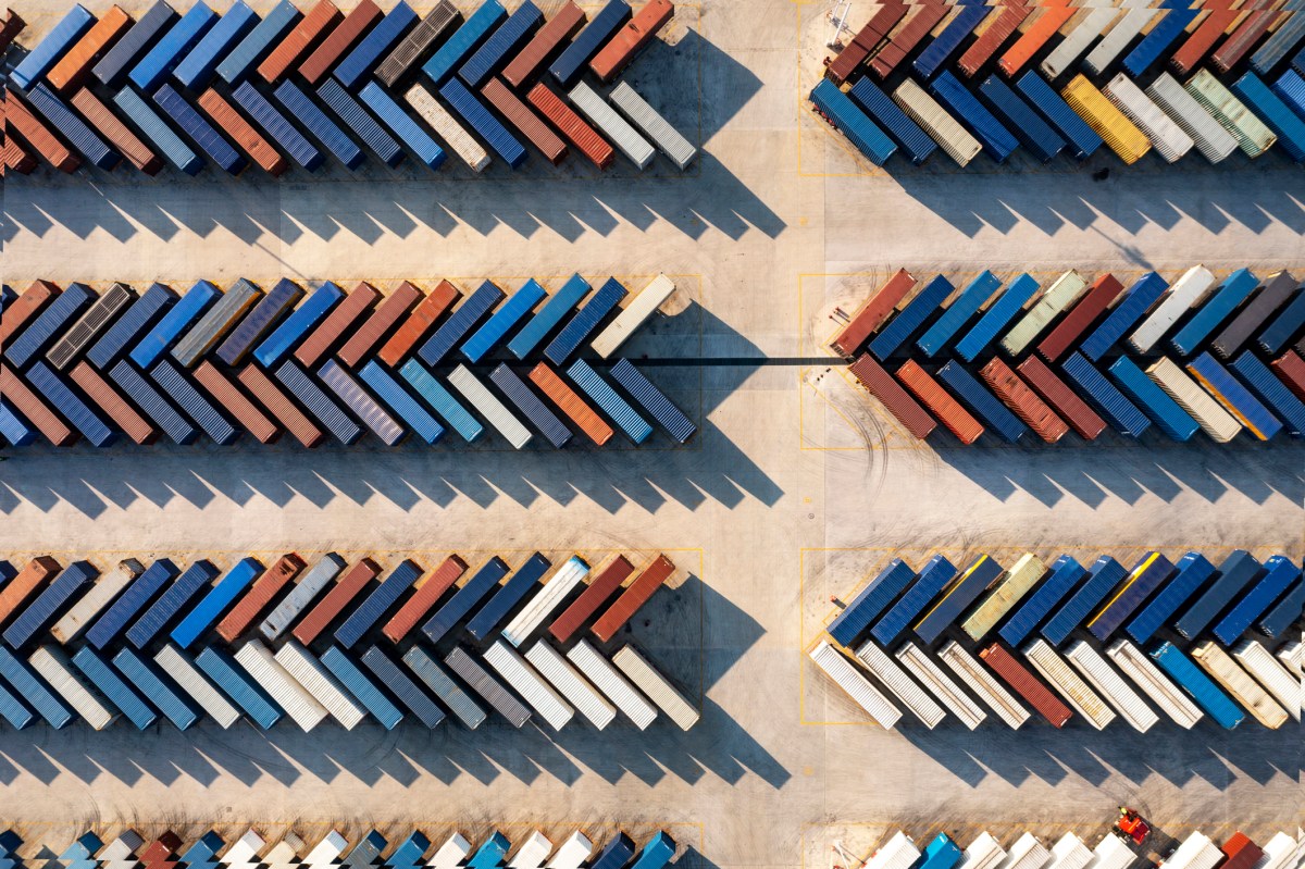 Aerial view of a distribution warehouse with truck and containers and road at Shanghai free trade zone,china.Top down shot looking directly down on rows of truck trailers and shipping containers, ready to be transferred between road and rail modes of transport, used in a post about freight forwarding startup GoFreight