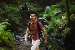 Man hiking in a forest wearing Odyssey camera pack