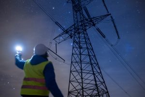 High voltage engineer working on power lines at night.