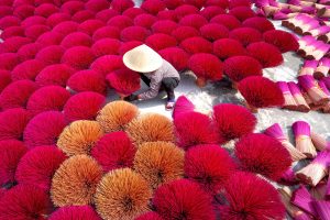 man in asian conical hat on incense production