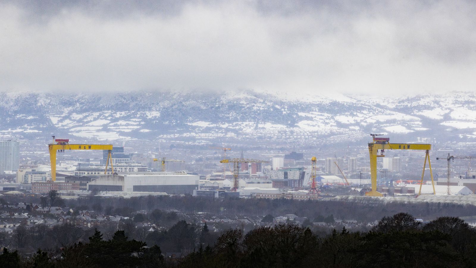 Low clouds over the snow covered Black Mountain behind the Harland & Wolff cranes on the east side of Belfast Lough. Much of the UK and Ireland is facing another day of cold temperatures and travel disruption after overnight lows dropped below freezing for the bulk of the country. A "cold plunge of Arctic air" has moved south across the whole country over the past few days, making it 5C-6C lower than usual for this time of year, the Met Office said. Picture date: Tuesday January 16, 2024.