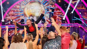 Chris McCausland celebrates his win, as Dianne Buswell holds the glitterball trophy aloft. Pic: PA