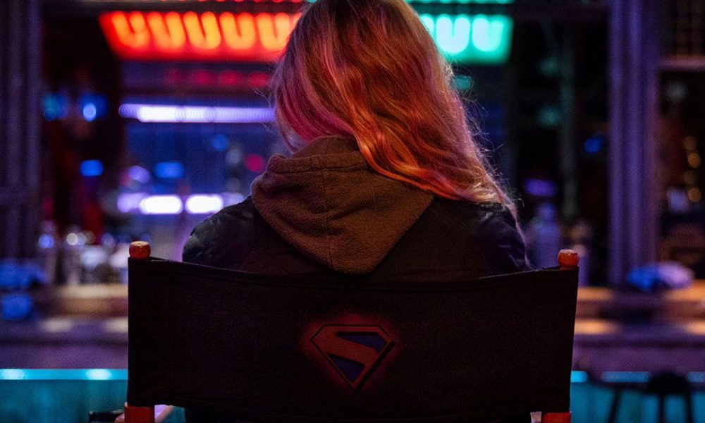 An image of Milly Alcock sitting on a chair with her back to camera on the set of Supergirl: Woman of Tomorrow