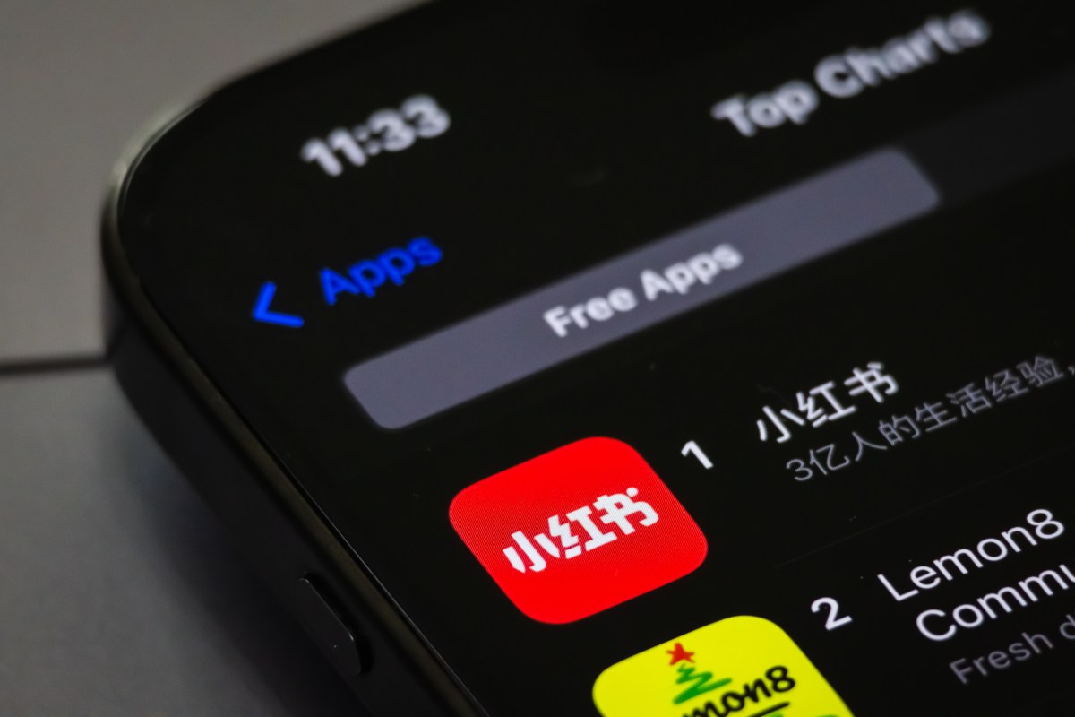 A smartphone screen displays the RedNote app (Xiaohongshu) ranking first in the Free Apps category on the App Store