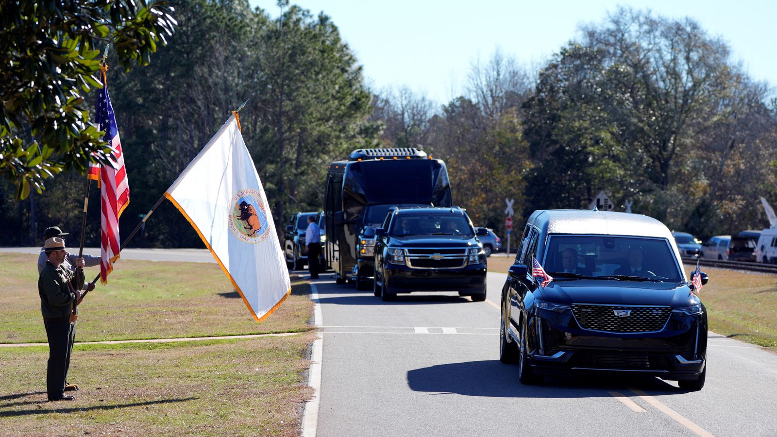 Members of the National Park Service watch as the hearse containing Jimmy Carter's coffin passes through his boyhood Farm in Archery, Georgia. Pic: Reuters