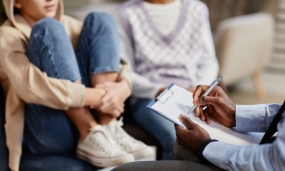 Close up of African-American psychologist taking notes on clipboard in therapy session for children. Pic: iStock