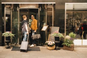 Friends talking while standing at doorway of hotel in city