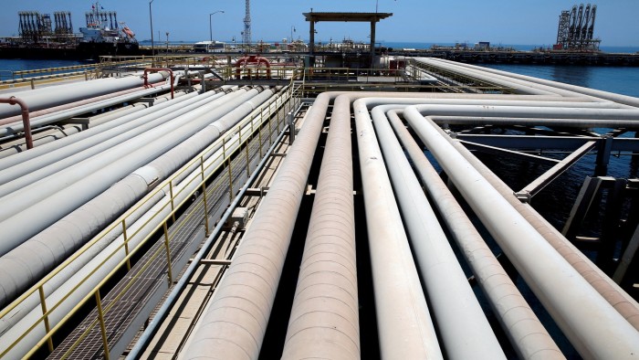 A network of large oil pipelines stretches across an industrial area at an oil refinery and terminal