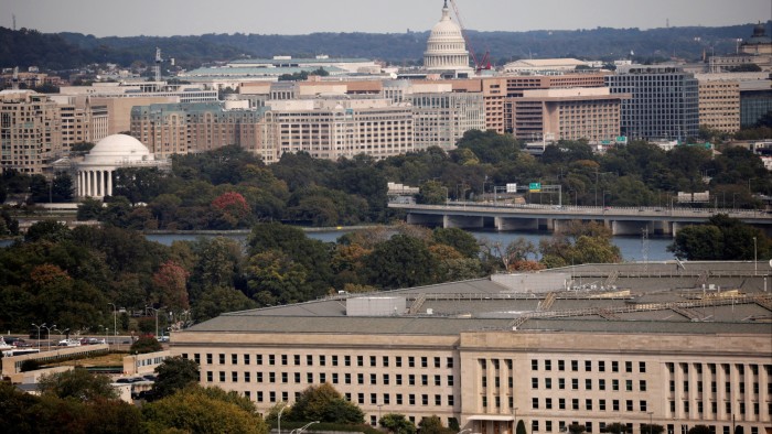 The Pentagon building in Arlington, Virginia, with the cityscape of Washington, DC, in the background. Prominent landmarks include the US Capitol and the Jefferson Memorial.
