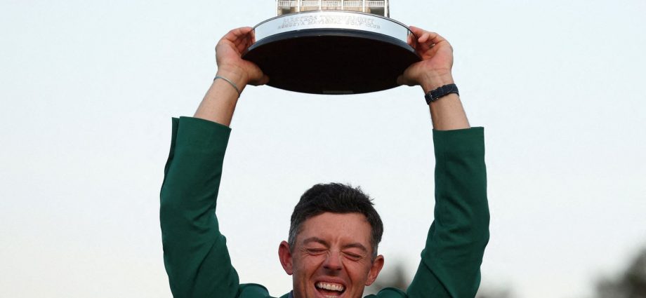 Rory McIlroy celebrates with his green jacket and the trophy after winning The Masters. Pic: Reuters