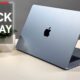 MacBook Air in sky blue on a white desk with a plant and a Black Friday sign.