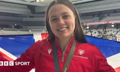Charlotte Gower holds up a Great Britain flag with a medal around her neck