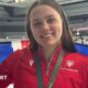 Charlotte Gower holds up a Great Britain flag with a medal around her neck