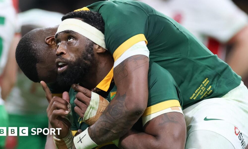 South Africa captain Siya Kolisi looks and points upwards as he is hugged by a team-mate
