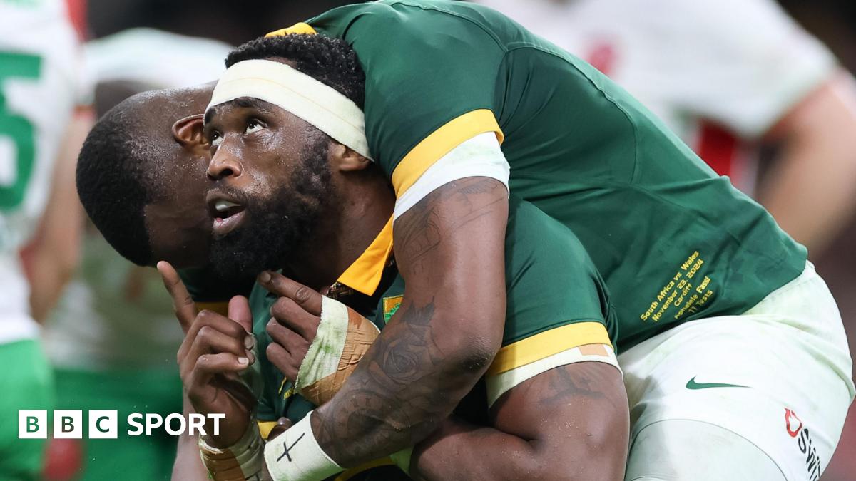 South Africa captain Siya Kolisi looks and points upwards as he is hugged by a team-mate