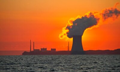 The sun rises behind a nuclear power plant cooling tower.