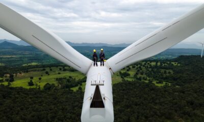 Two Electric engineer wearing Personal protective equipment working on top of wind turbine farm; climate tech investor survey
