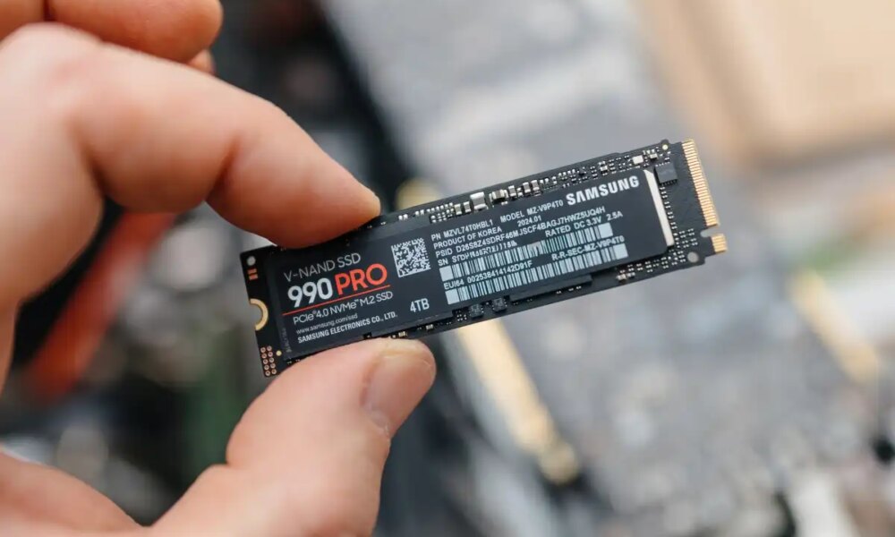 Man holding Samsung 990 PRO SSD between fingers over exposed laptop hero