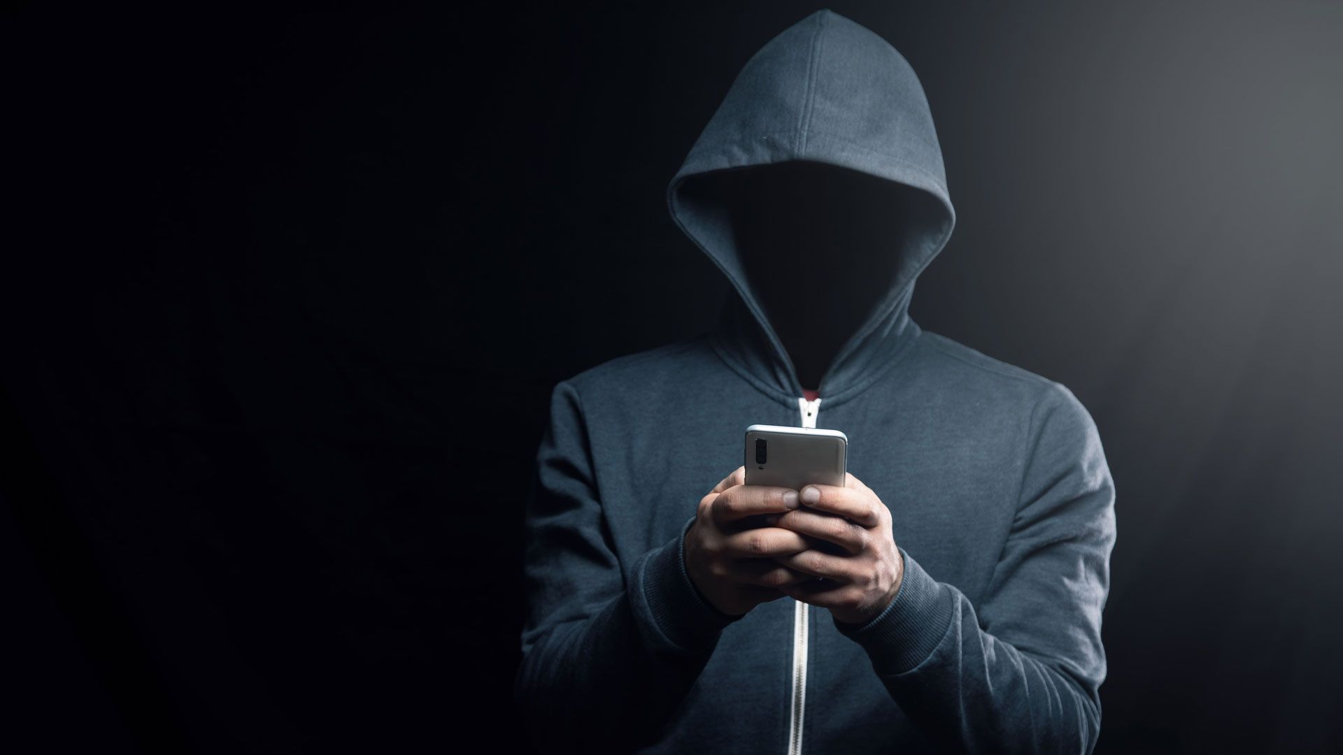 A dark figure in a hoodie representing a hacker.