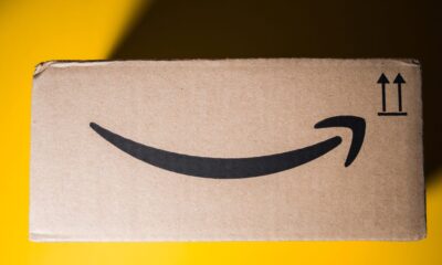 a side view of an old Amazon delivery box against a bright yellow background. the top left corner is covered in shade from the box&apos;s shadow