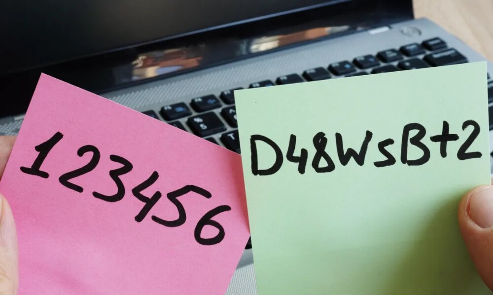 Two different passwords written separately on a pink and green post-it note in front of a laptop