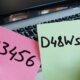 Two different passwords written separately on a pink and green post-it note in front of a laptop