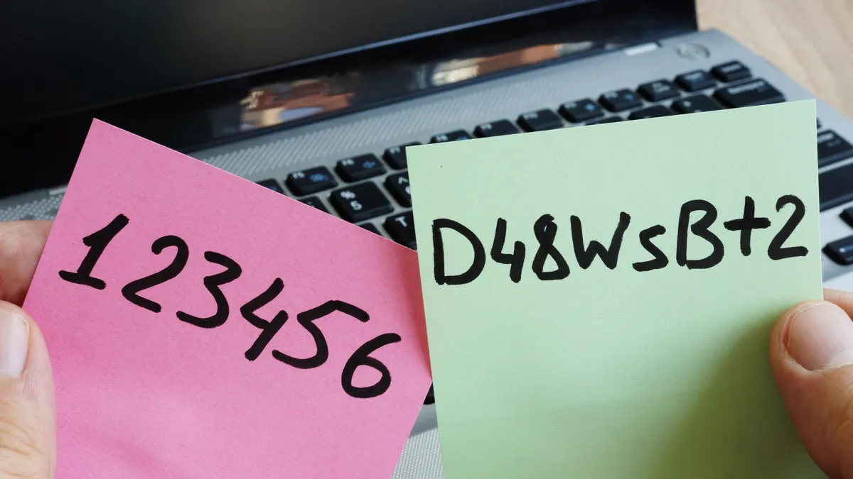 Two different passwords written separately on a pink and green post-it note in front of a laptop