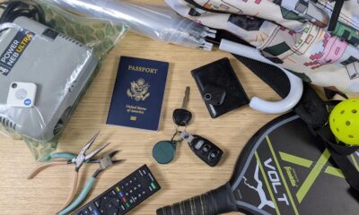 bluetooth trackers and various trackable items on bamboo desk including a passport, car keys, and umbrella