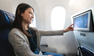 woman traveling by plane and watching onboard entertainment
