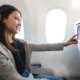 woman traveling by plane and watching onboard entertainment