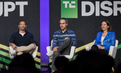 Three speakers talk on a stage with a black backdrop.