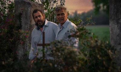 a movie still of Adam Sandler and George Clooney standing in what appears to be a park or forest