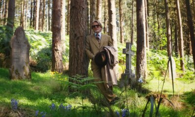 man stands against a tree in an old cemetery