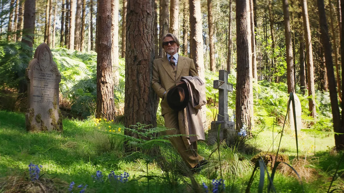 man stands against a tree in an old cemetery