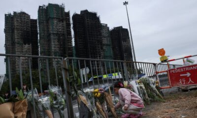 A girl places flowers in front of the fire-damaged residential blocks at Wang Fuk Court. Pic: Reuters